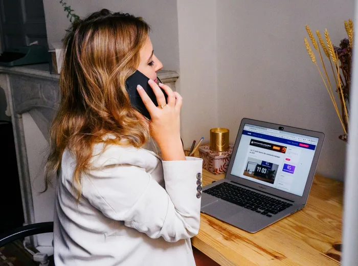 Personne au téléphone près de son ordinateur portable, en train d'échanger avec un client