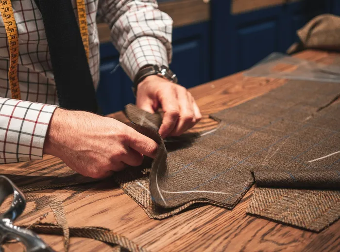 Tailleur mesurant et ajustant un tissu en tweed sur mesure dans son atelier