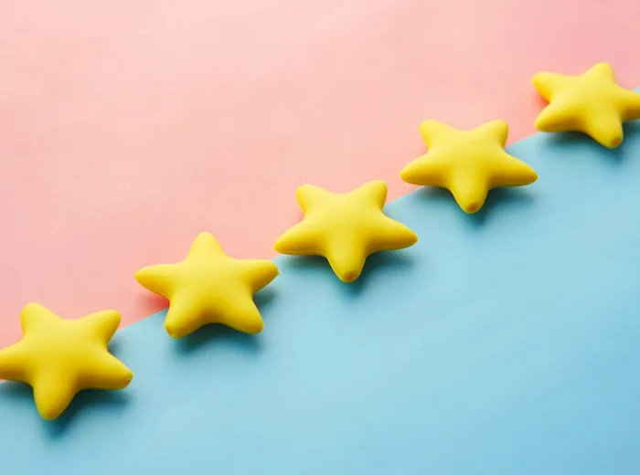Cinq étoiles jaunes alignées en diagonale sur un fond bicolore rose et bleu, symbole de notation client