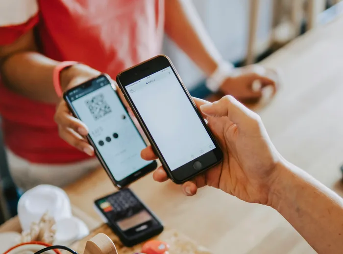 Client tenant un smartphone affichant un QR code au comptoir d'un café, pour laisser un avis en quelques secondes